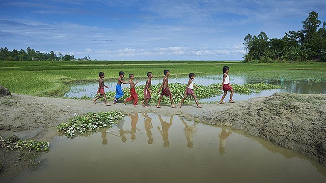 Barn går längs en eroderad stig i Kunderpara, en by på en ö i Brahmaputrafloden i norra Bangladesh.