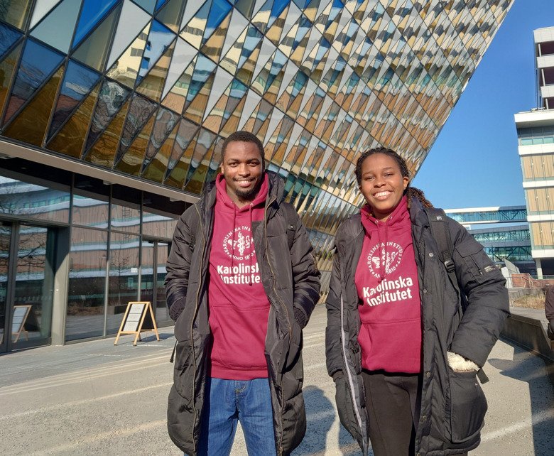 Two students with KI shirts outside of Aula medica in campus solna.