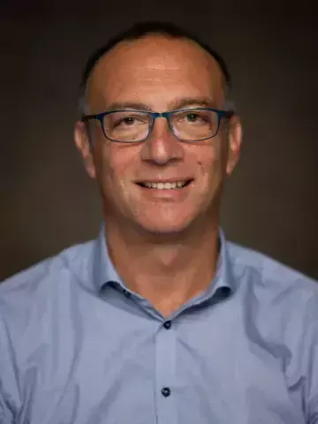 Porträtt av man i blå skjorta.