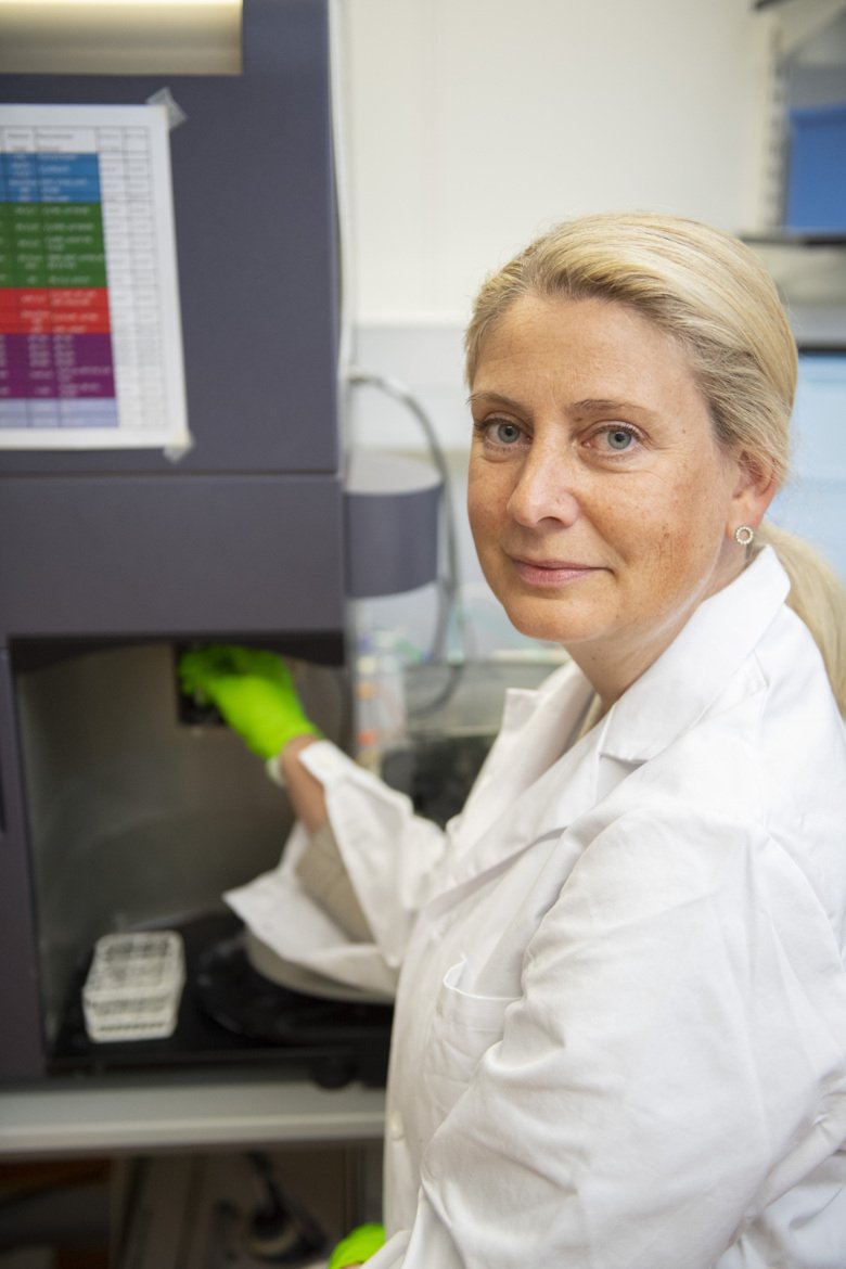 Porträtt av Anna Smed Sörensen i labbet. Hon är blond, har vit rock och gröna handskar.