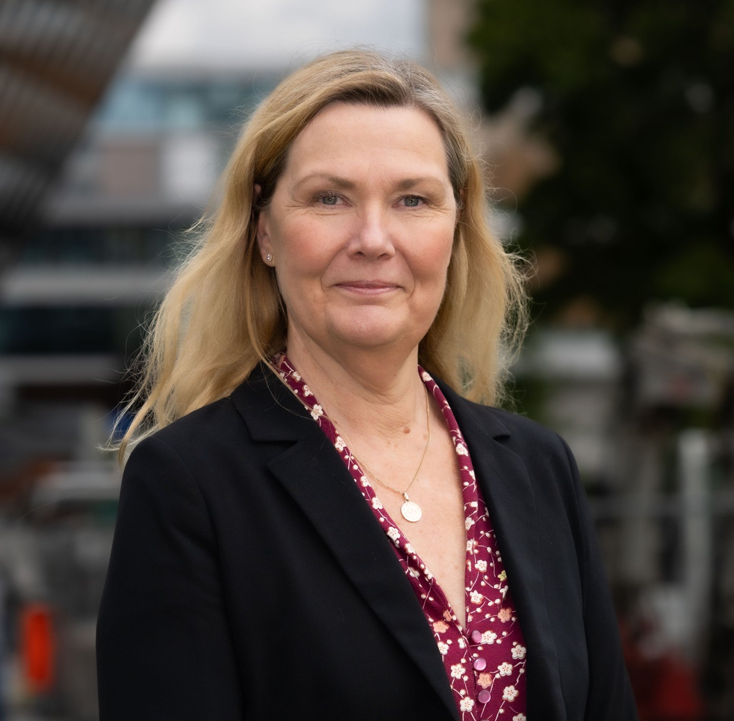 Porträtt av kvinna i svart kavaj med blont hår.