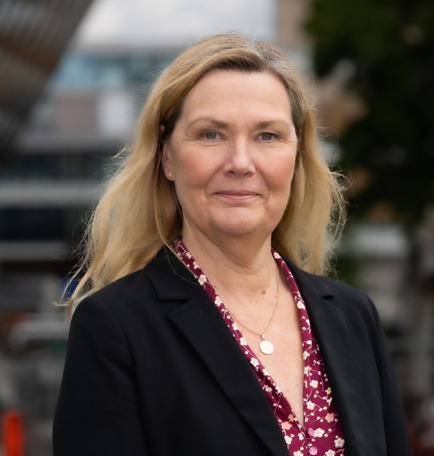 Porträtt av kvinna i svart kavaj med blont hår.