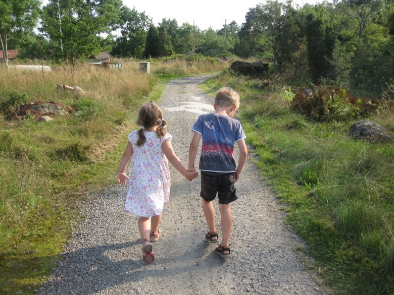 Två barn på promenad på en grusväg