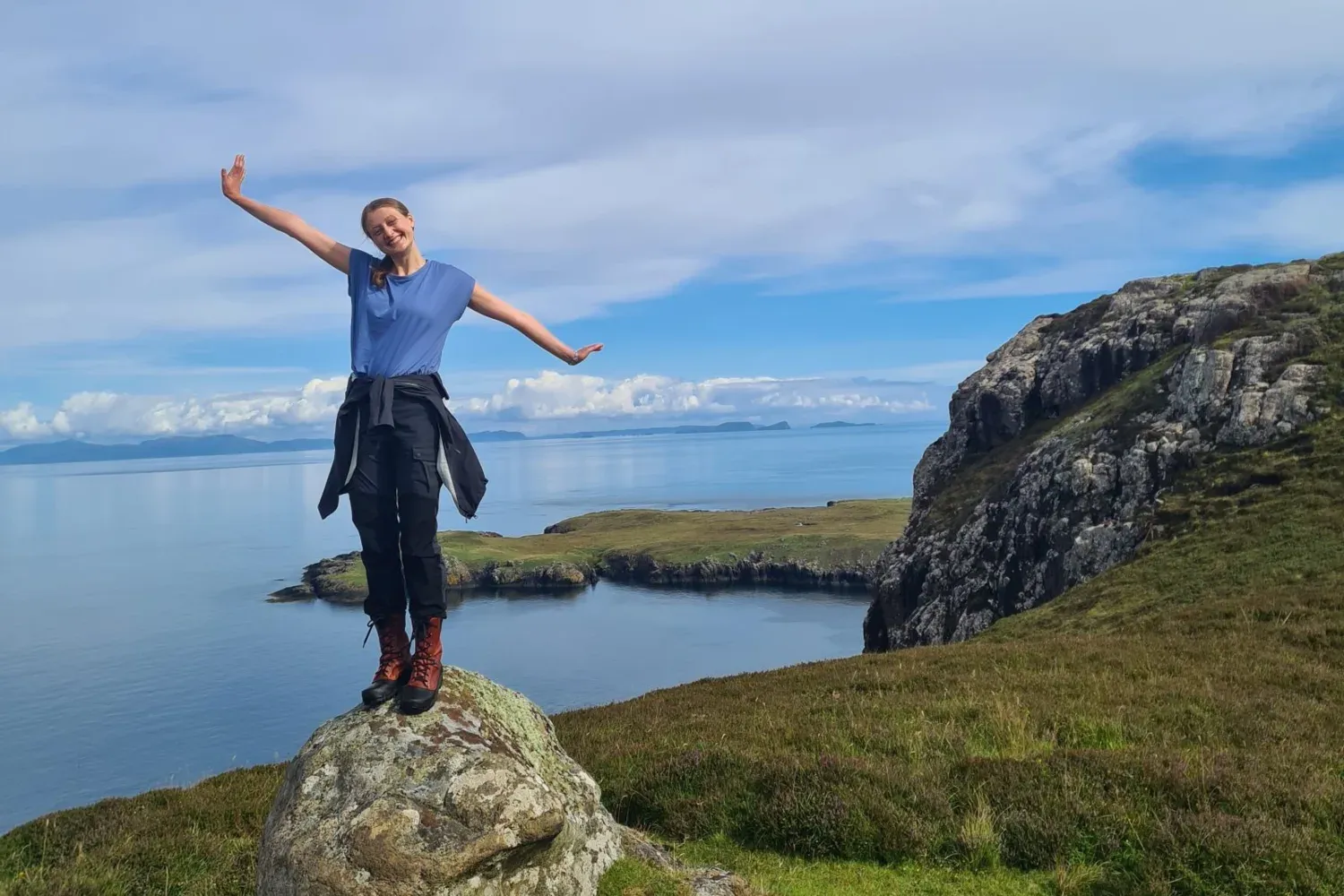 Anna Frisk på en sten framför vatten under en resa