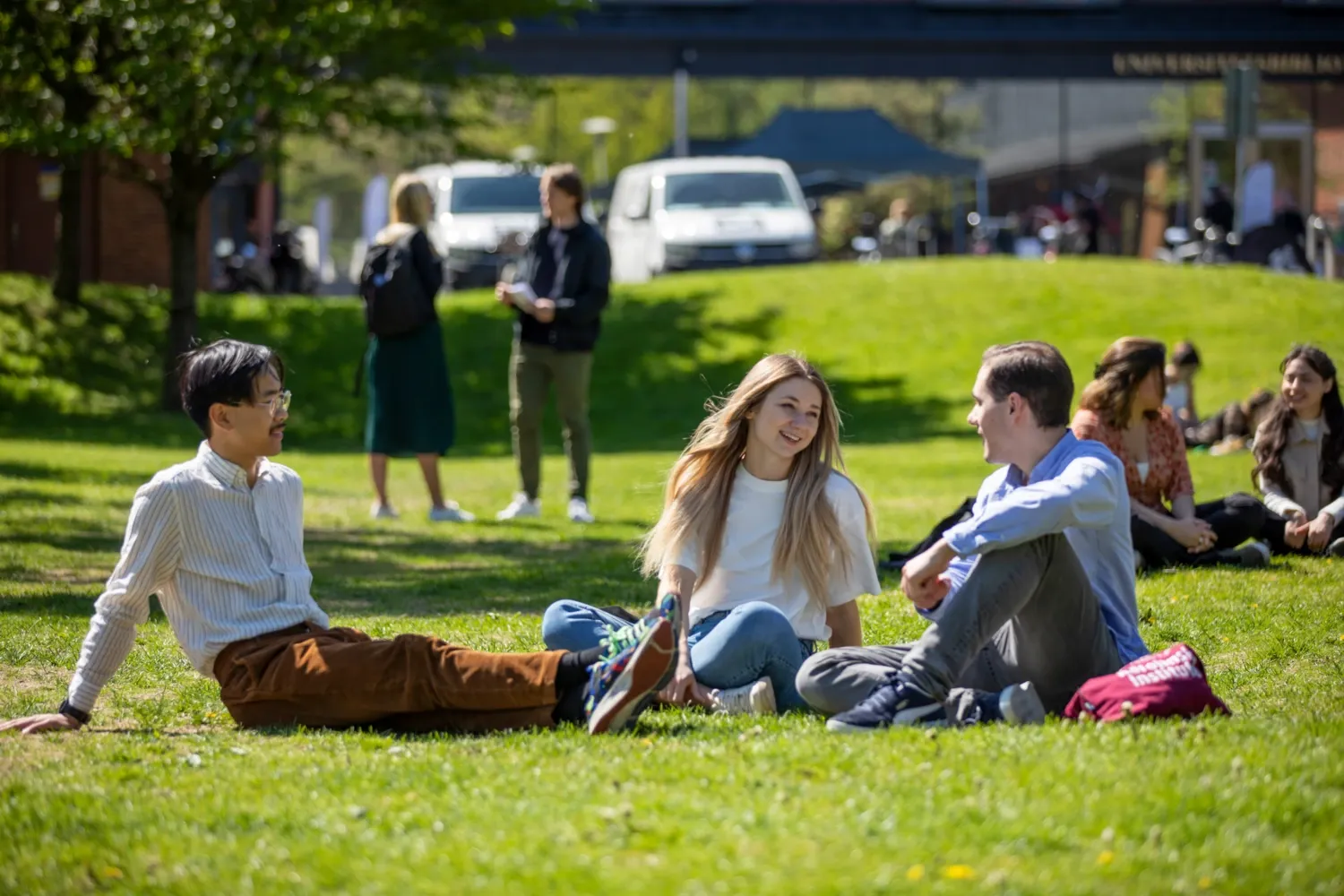 Studenter utomhus på campus Solna en solig vårdag 2022. || Studenter utomhus på campus Solna. || Studenter utomhus på campus Solna.