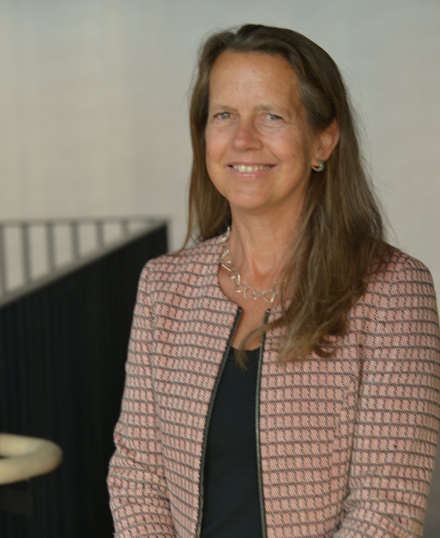 Porträtt av kvinna i ljus mönstrad väst.