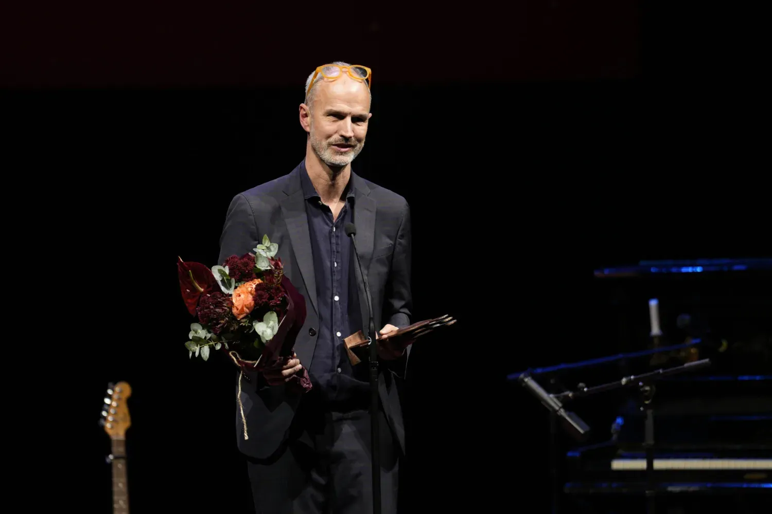 Christian Rück på scen med blombukett och pris.