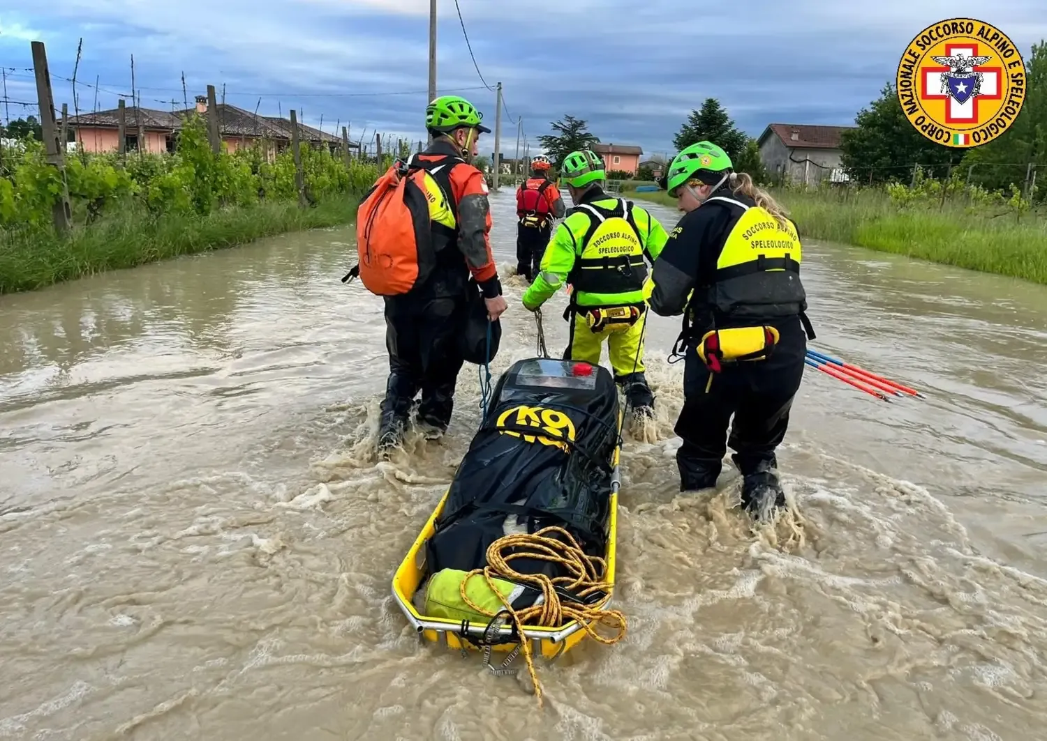 Tre räddningstjänstarbetare drar en flytande bår på en översvämad gata