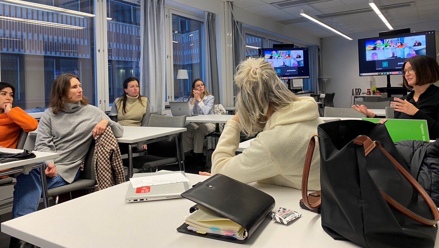 Studenter vid doktorandkursen ”Hållbar hälsa och Agenda 2030” sitter vid bänkar i en lärosal och diskuterar med varandra.