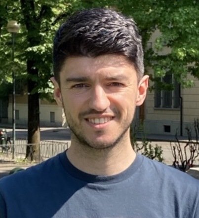 Porträttbild av mörkhårig man med mörkblå tröja.