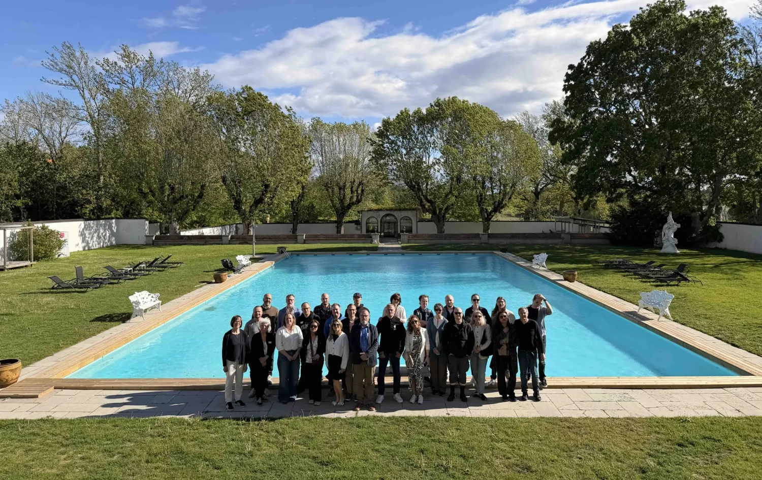 Gruppbild på ca 20 personer ståendes framför en pool på en konferensanläggning.