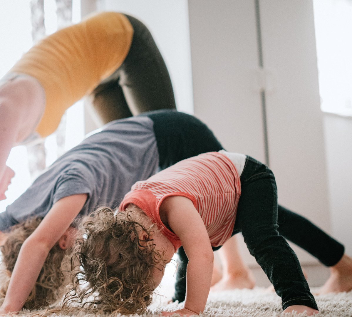 En vuxen som gör yogaposer tillsammans med mindre barn.