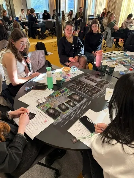 Studenter deltar i en samarbetsinriktad workshop vid runda bord med kort på bordet