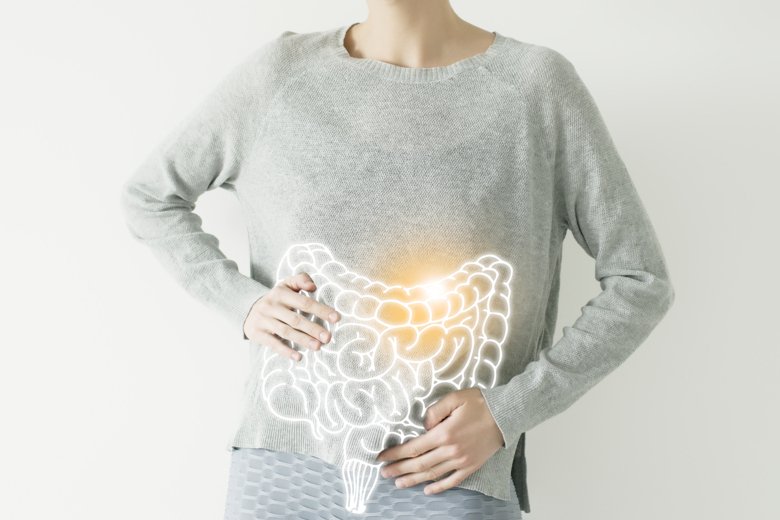 Person håller sig för magen med illustrerat tarmsystem över tröjan.