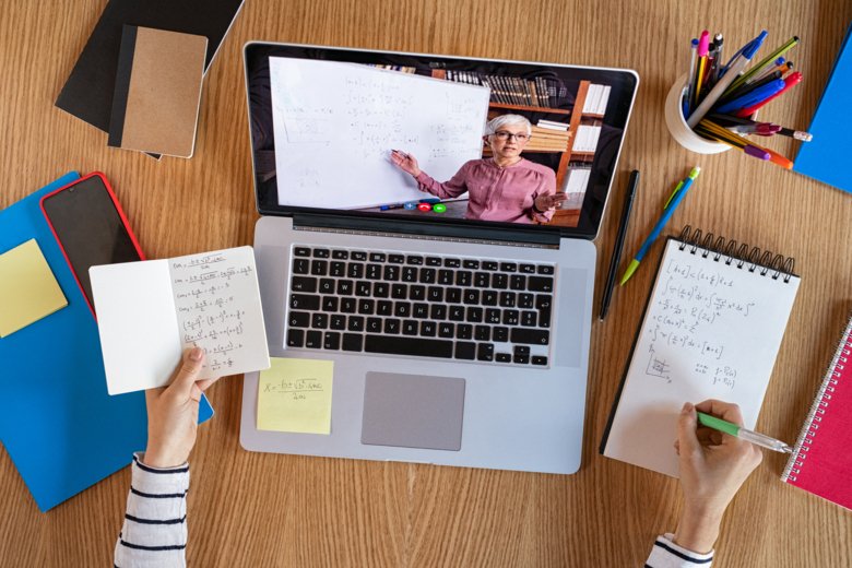 Laptop med online-möte står på bord med anteckningsblock