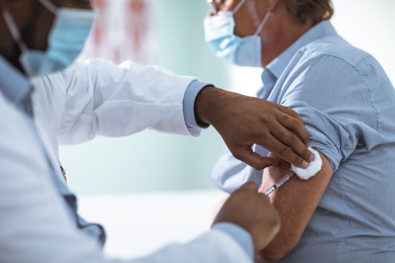 Person med munskydd blir vaccinerad i armen