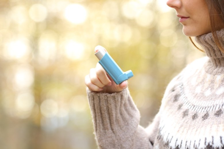 Kvinna som håller astmainhalator för att använda i vintertid