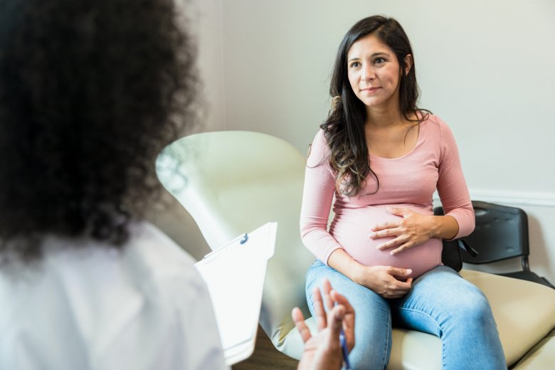 Gravid kvinna sitter och pratar med en läkare.