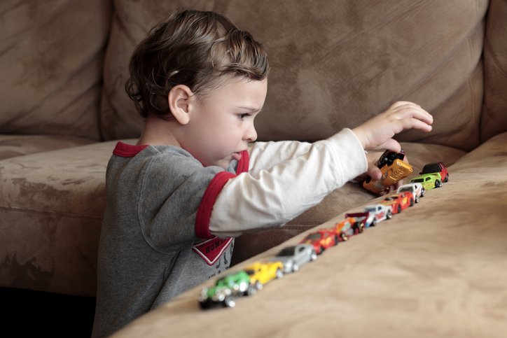 Liten pojke med autism som leker med bilar