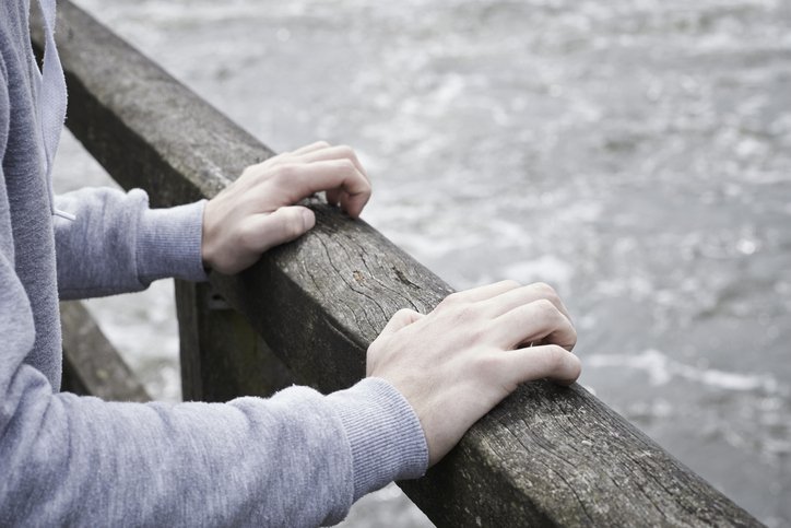 Deprimerad man som står på en bro och funderar på självmord