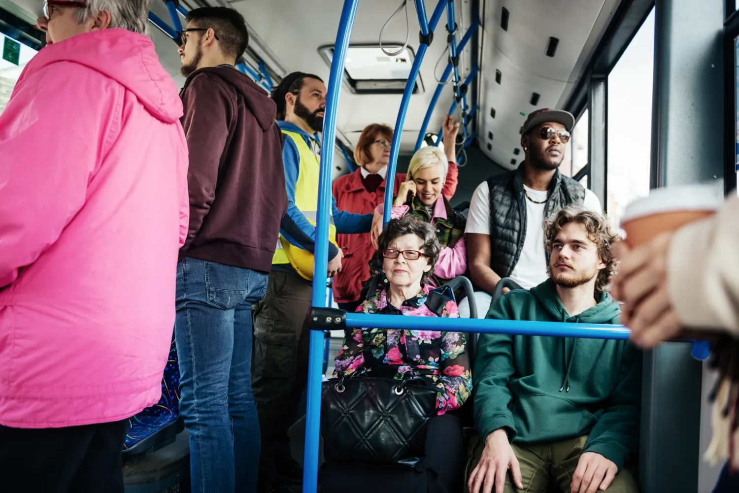 Personer stående och sittandes på en fullpackad buss.