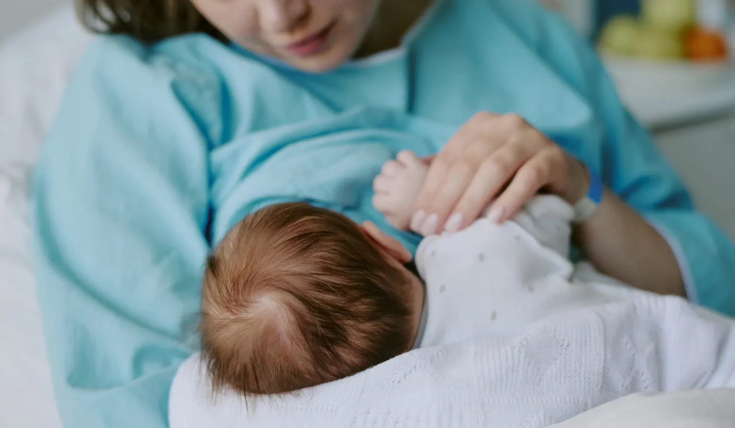 En kvinna håller ett inlindat nyfött barn i sin famn.