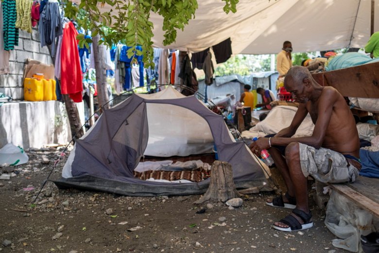 En man sitter bredvid hans tält i ett läger för internflyktingar i Port-au-Prince, Haiti.