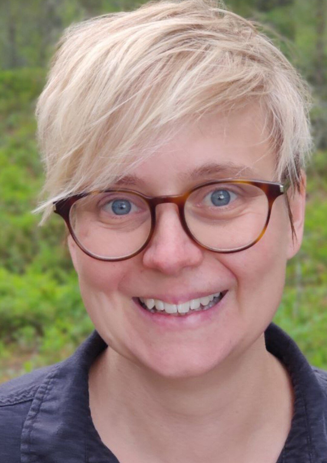 Porträttfoto av forskaren Helena Tinnerholm Ljungberg i blå skjorta och utomhus.