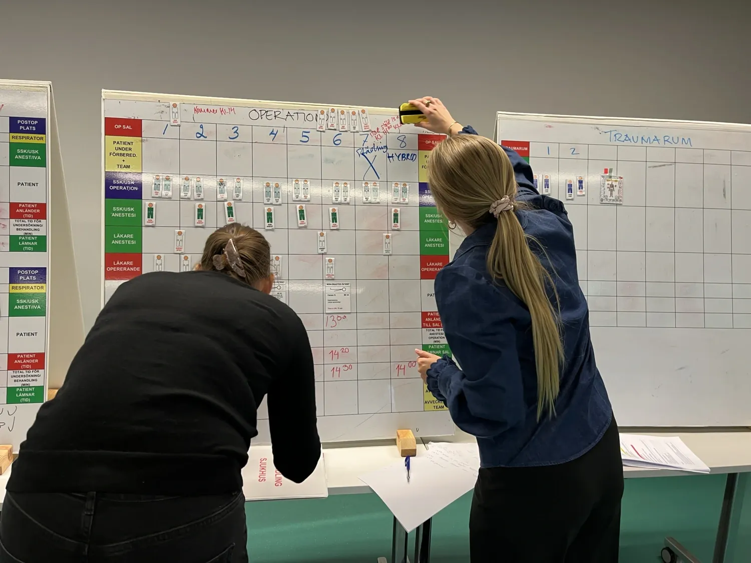 Två personer står framför en whiteboard-tavla