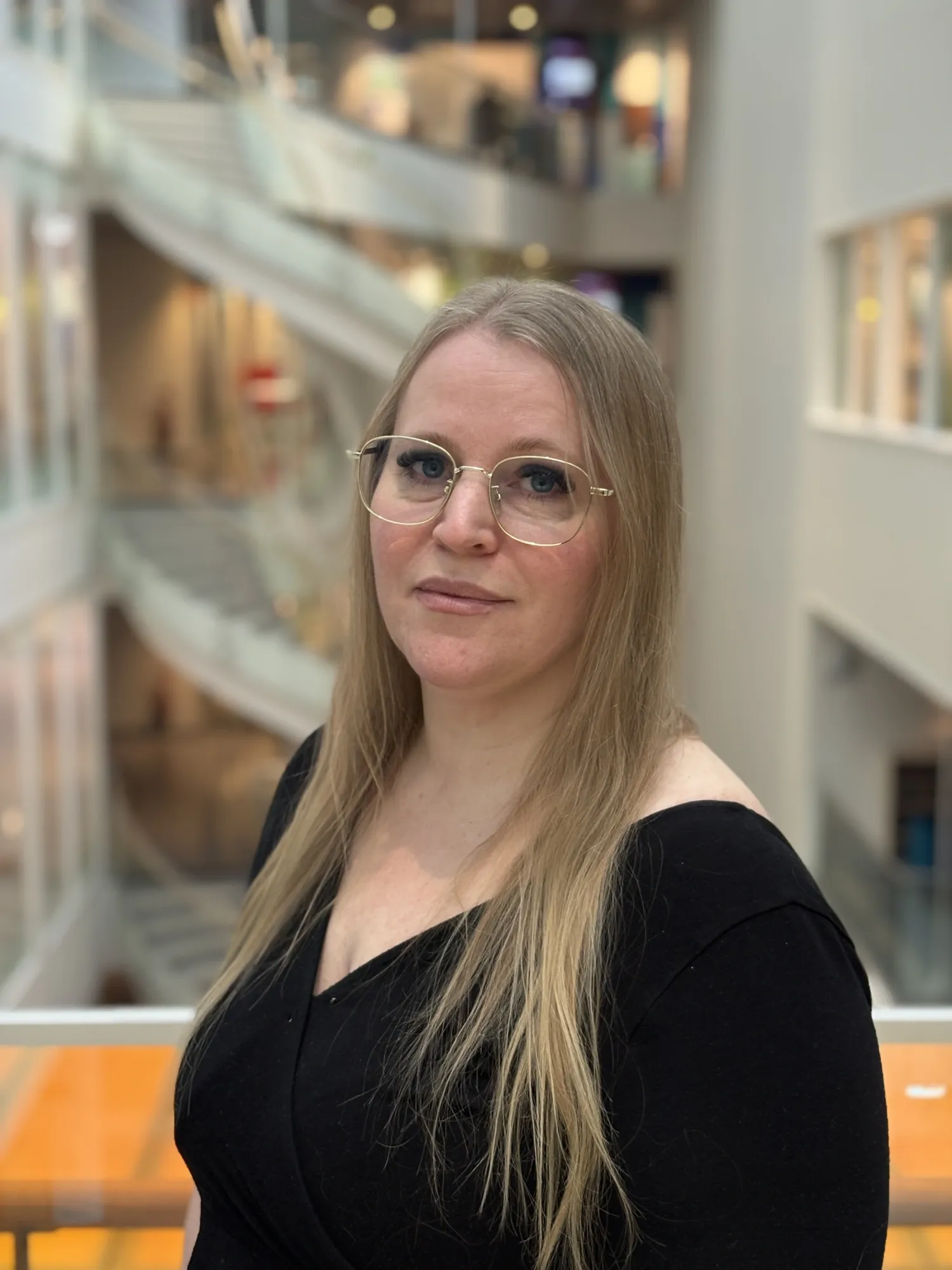 Porträttbild på blond kvinna i glasögon och svart tröja.