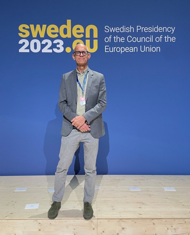 En man står framför en skärmväg där det står EU presidency 2023 Sweden