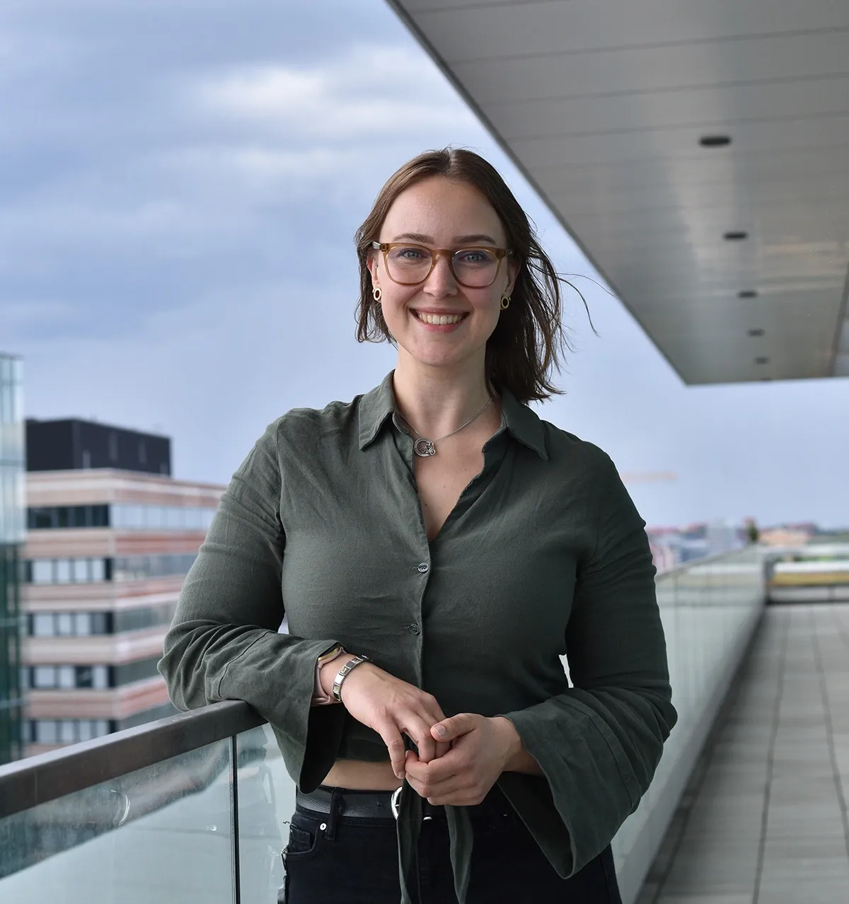 Porträtt av Vilma Alanko, doktorand vid avdelningen för klinisk geriatrik, NVS, ståendes utomhus på en terrass högt upp i Bioclinicum.