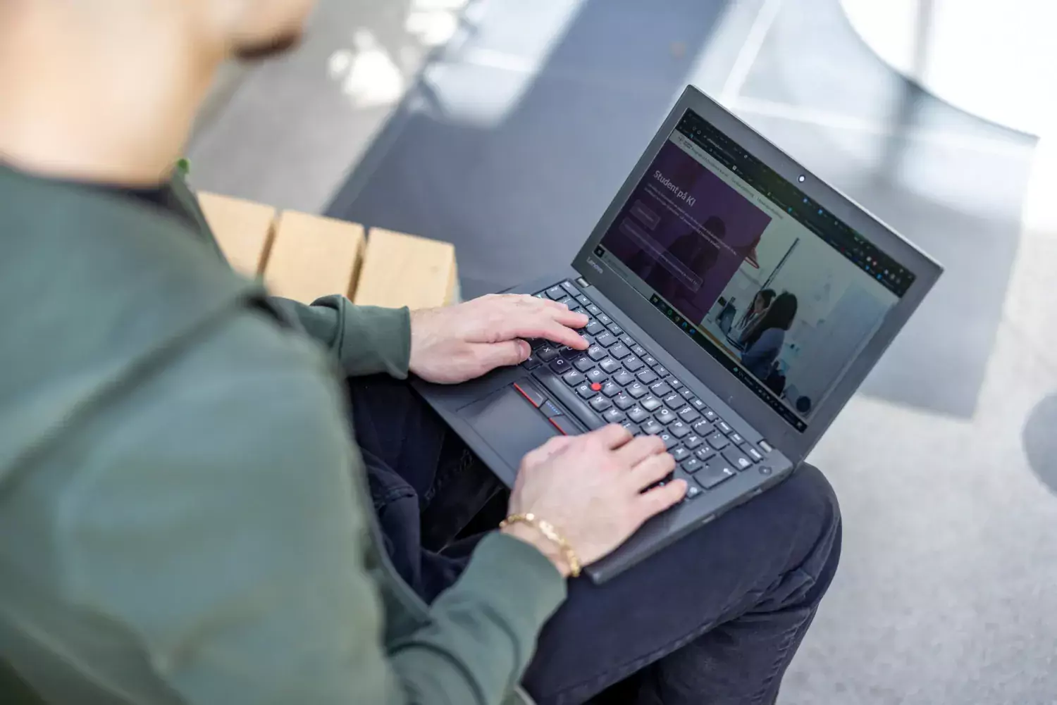 En student sitter med sin dator i knät och surfar på KI:s webb.