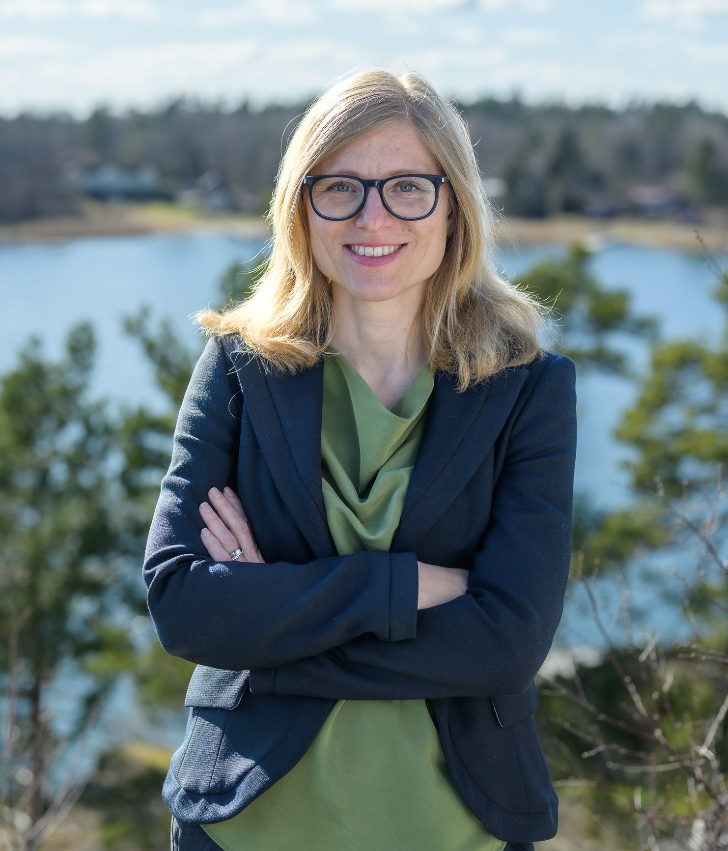 Porträtt av Kajsa Söderhielm, doktorand vid avdelningen för arbetsterapi, NVS, taget ute i naturen med grönska och vatten i bakgrunden..