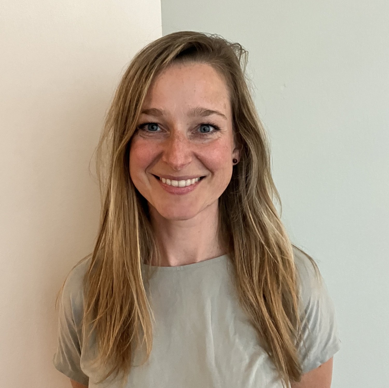 Närbild av Laura Wesseldijk, med händer bakom ryggen och tvåfärgad bakgrund.