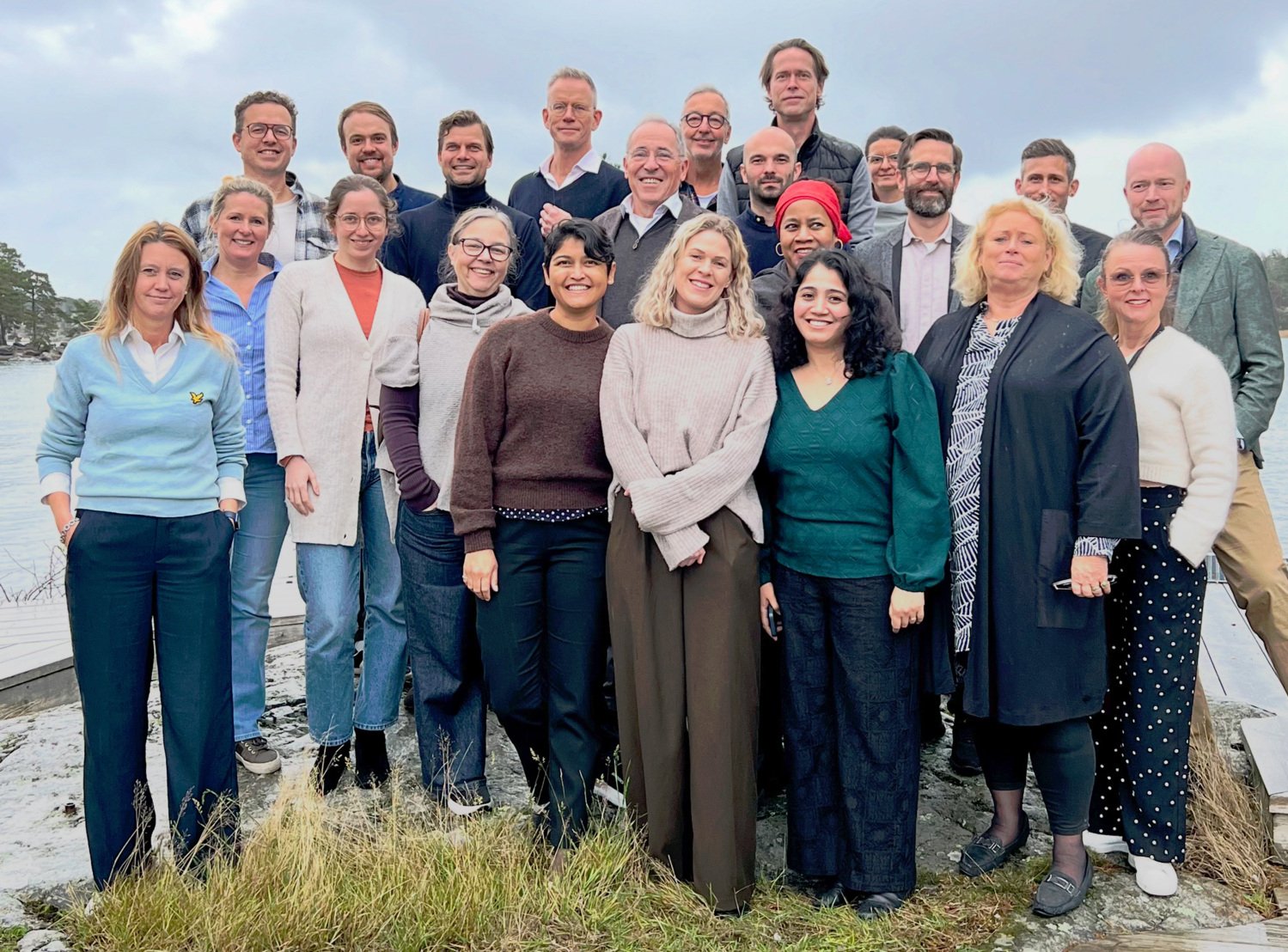 Gruppbild med 22 glada personer på en klippa utomhus