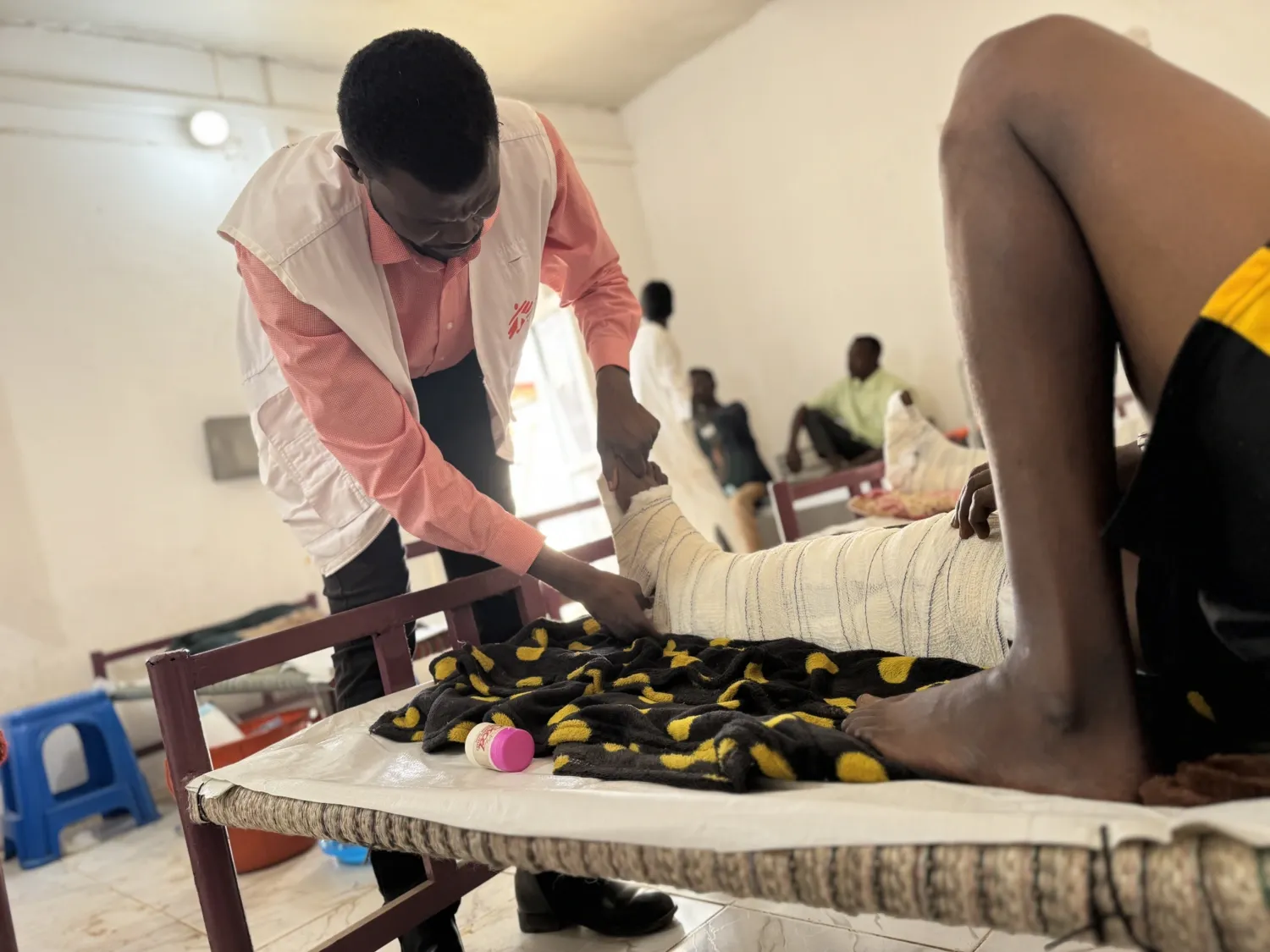 Läkaren Abubaker Abdalla justerar förbandet på en patient med skottskada på Tawila-sjukhuset i Darfur.