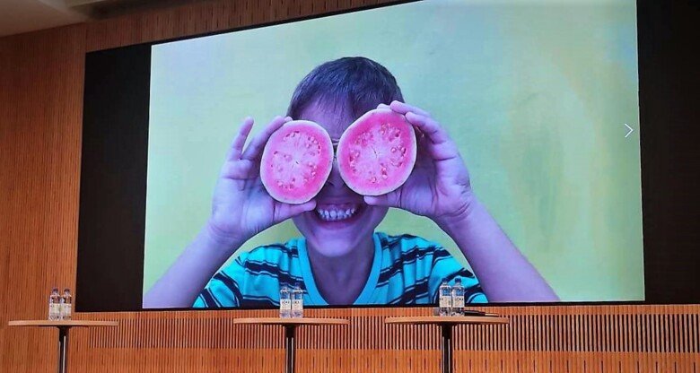 bild på projekturduk med omslaget till rapporten. Bild på barn med frukt/grönsak för ögonen.