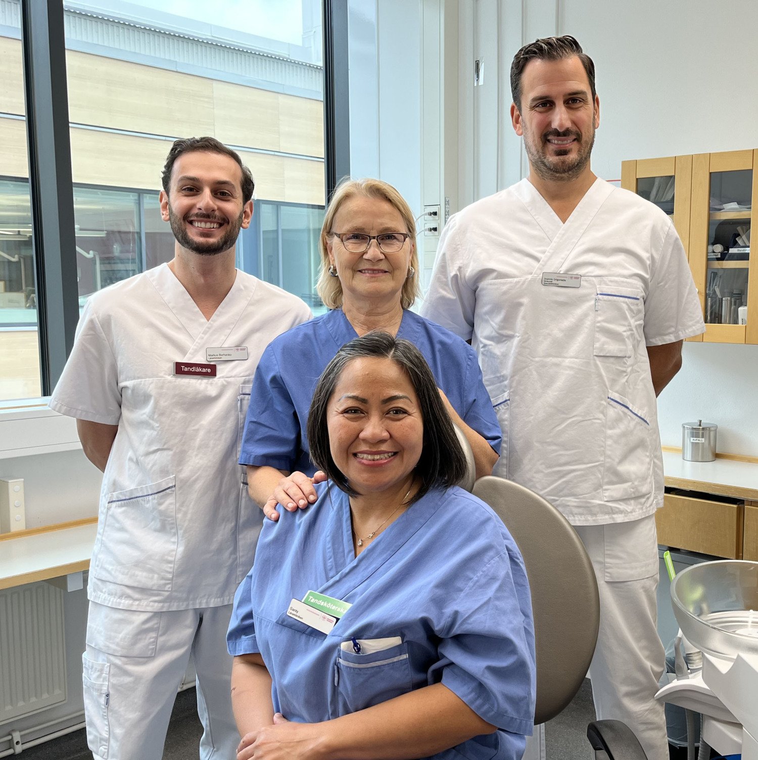 två tandläkare och två tandsköterskor i ett behandlingsrum för tandläkare