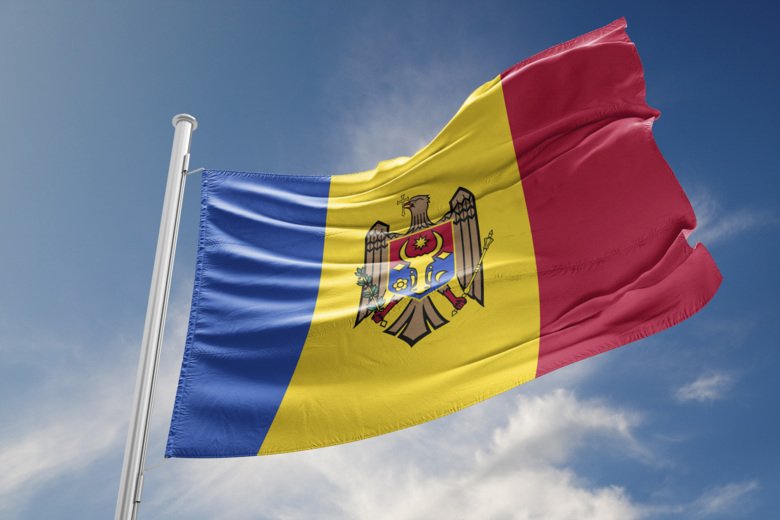 Moldaviens flagga på flaggstång mot blå himmel med lätta moln