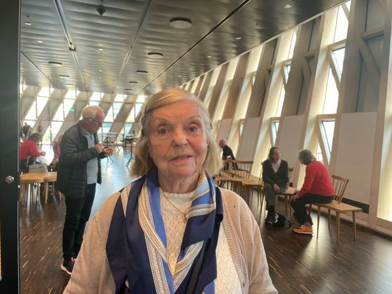Porträtt av Myrna 87 år, en av de många studiedeltagarna i SNAC-K-studien, i Aula Medica. Flera andra deltagare står och sitter i bakgrunden.