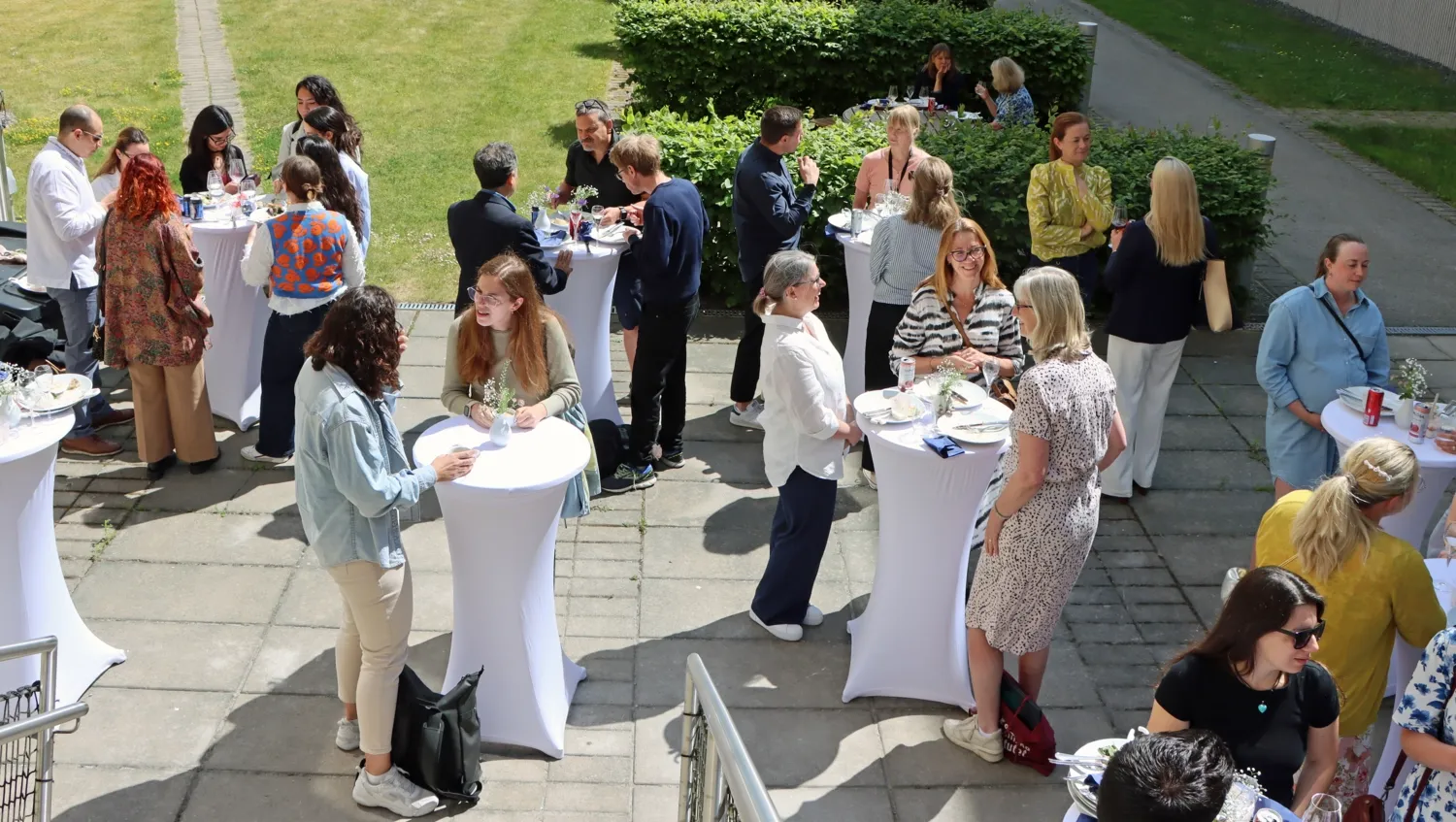 Folk står på baksidan av ANA 23 vid ståbord och äter av sommarlunchen