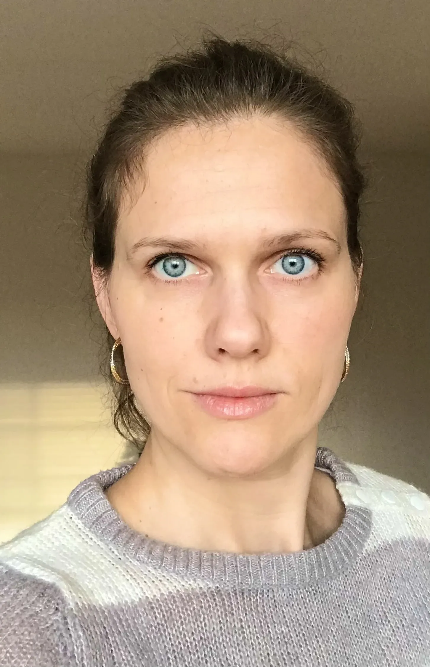 Porträttfoto av kvinna med blå ögon och uppsatt hår.