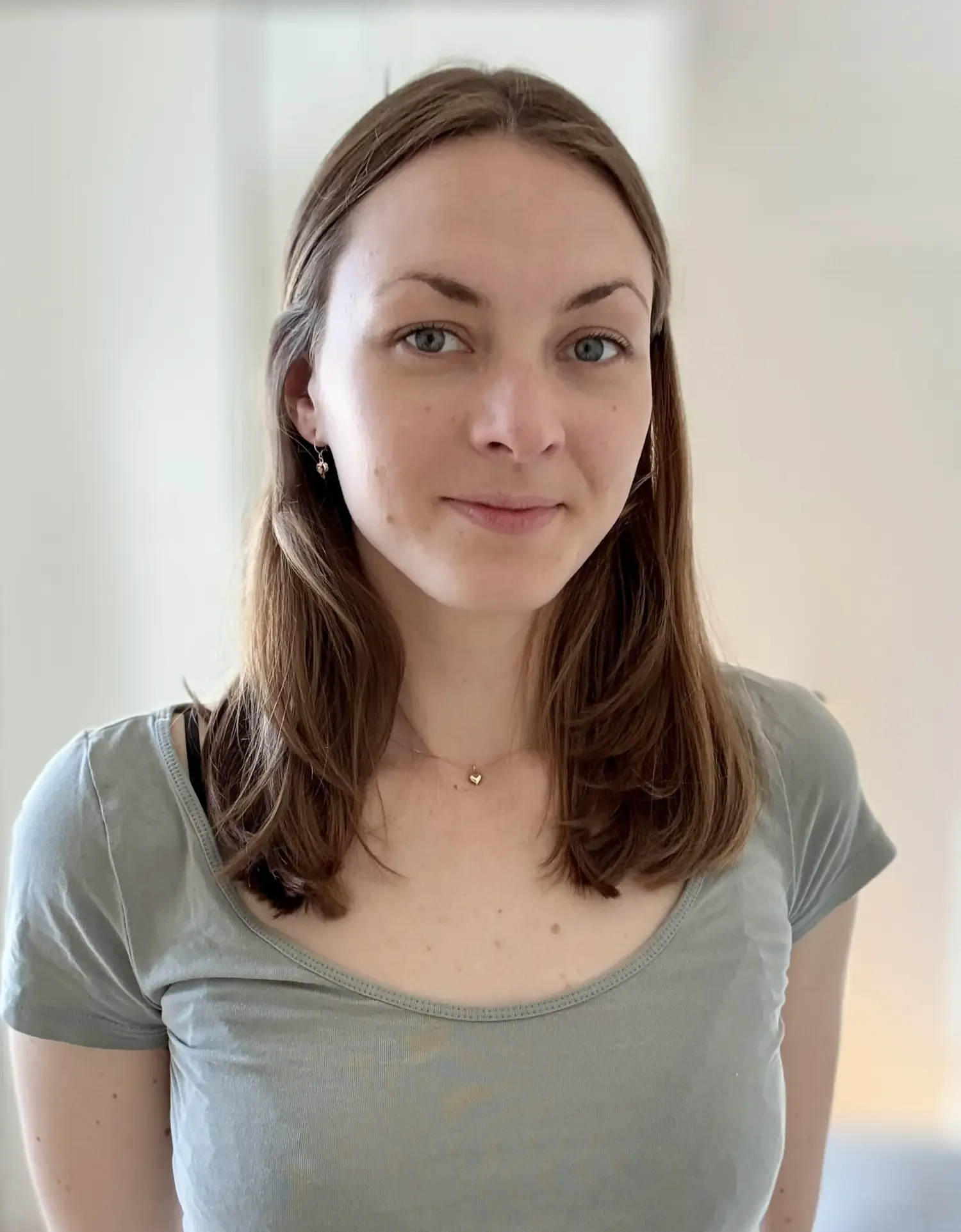 Porträtt av kvinna med mörkt hår och ljusgrå t-shirt.