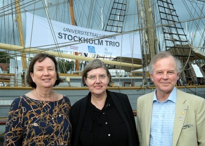 Rektorerna står framför en banderoll med texten "Stockholm trio".