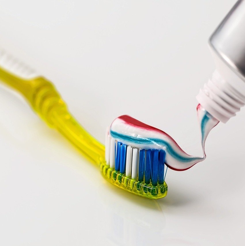 gul tandborste med flerfärgad tandkräm