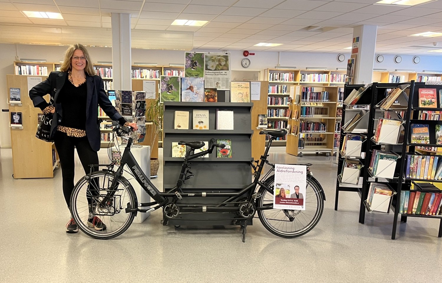 Pernilla Alencar Siljehag har avslutat tandemturen och står nu i biblioteket lutad mot tandemcykeln.
