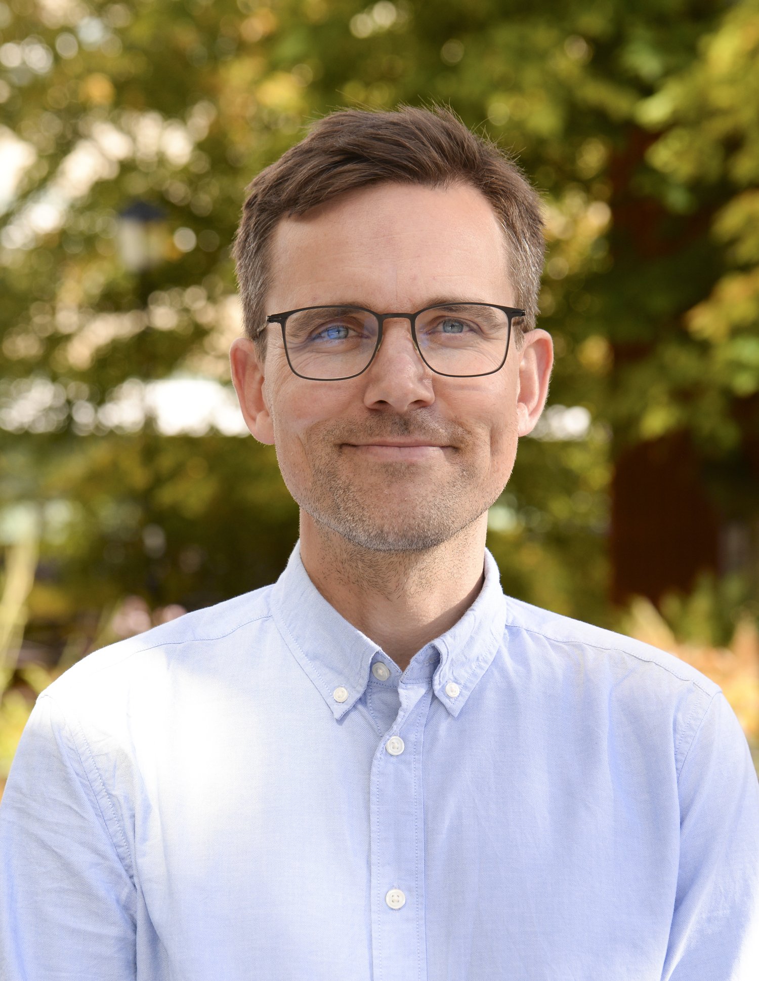 porträtt av man i blå skjorta.