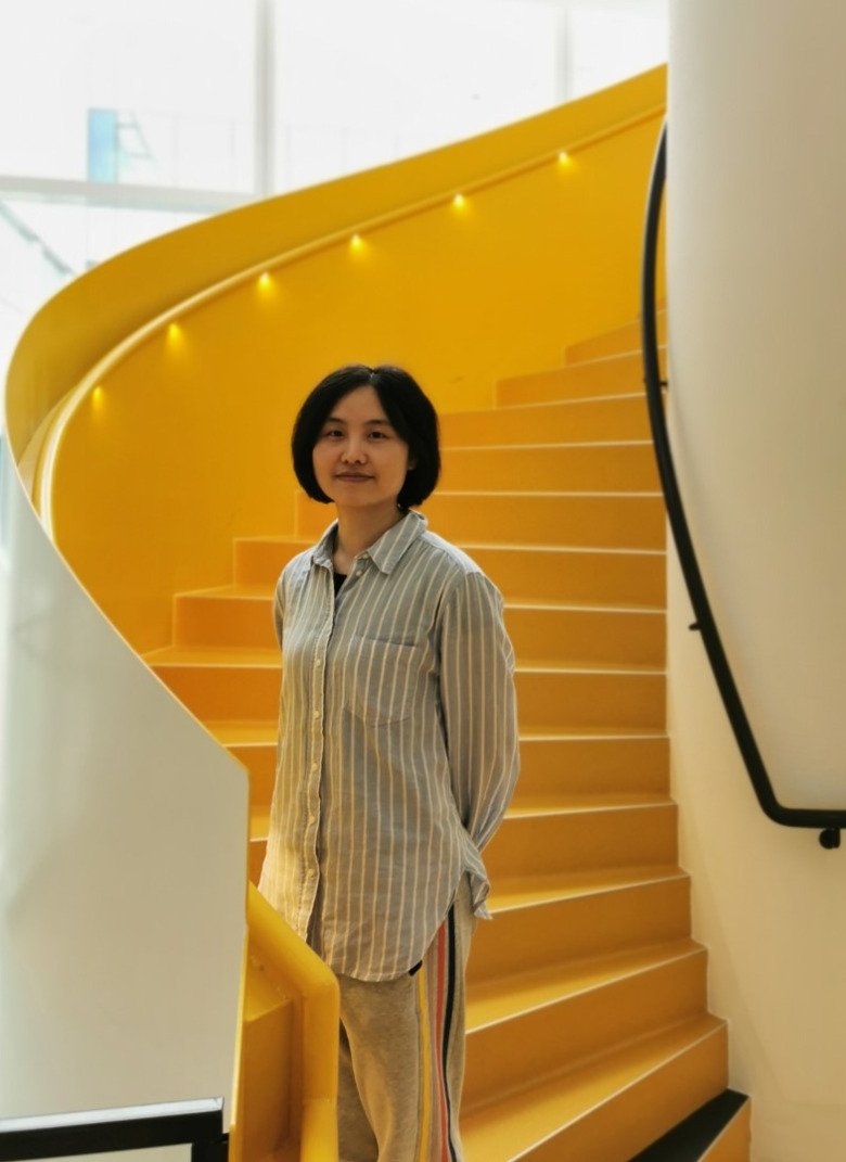 Tingting Xu, doktorand vid sektionen för neurogeriatrik, NVS, ståendes i en gul, spiraltrappa..