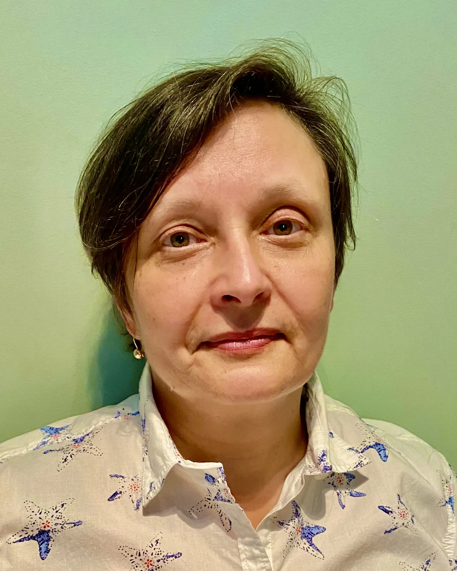 Porträtt av en kvinna med kort mörkt hår, iklädd en ljus skjorta.